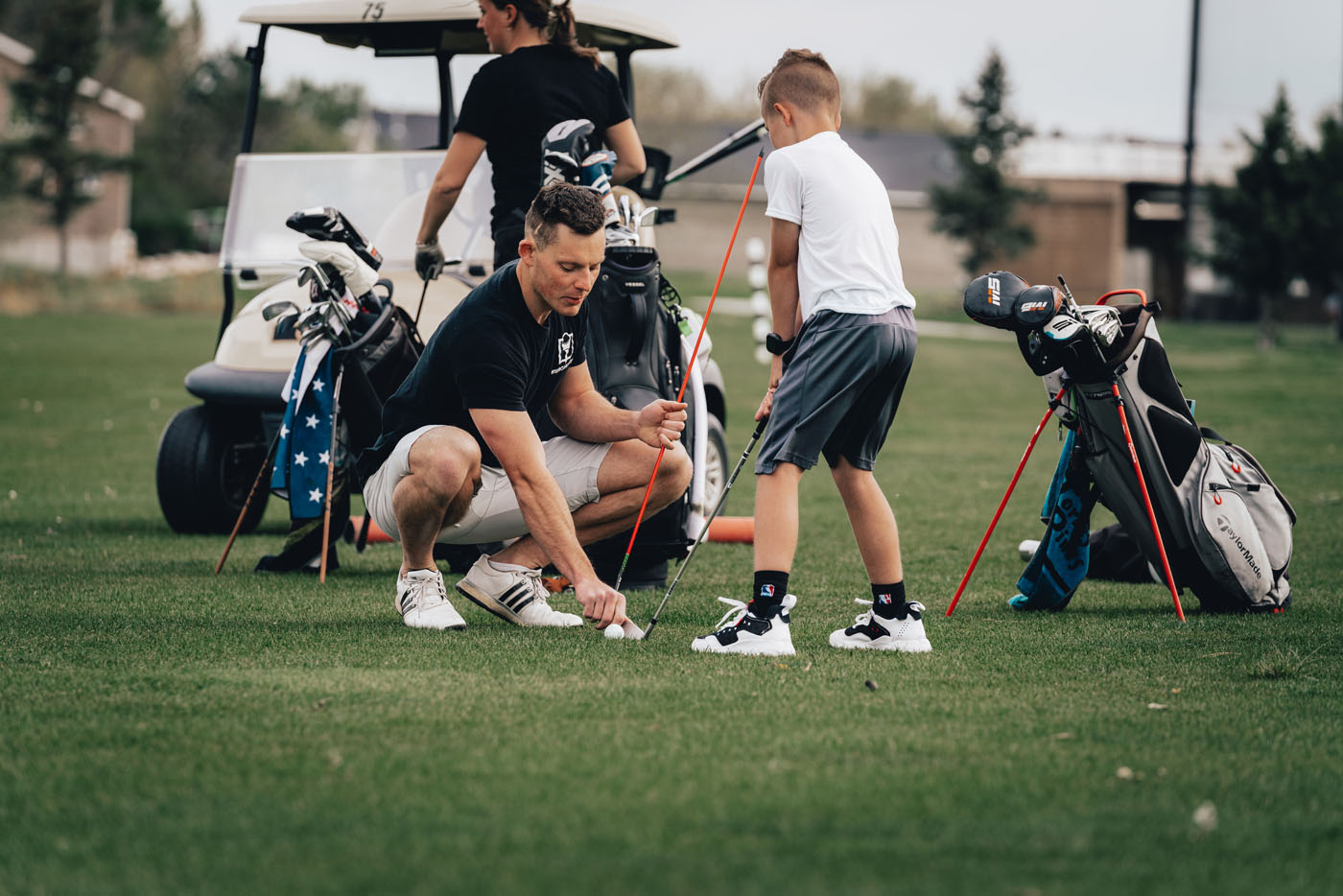 A Tee Box employee working with a group of kids on a golf course in Gilbert, AZ.